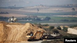 FILE - An Israeli military armored personnel carrier, a tank and a bulldozer are seen next to the border with the Gaza Strip, in southern Israel, July 11, 2019. 