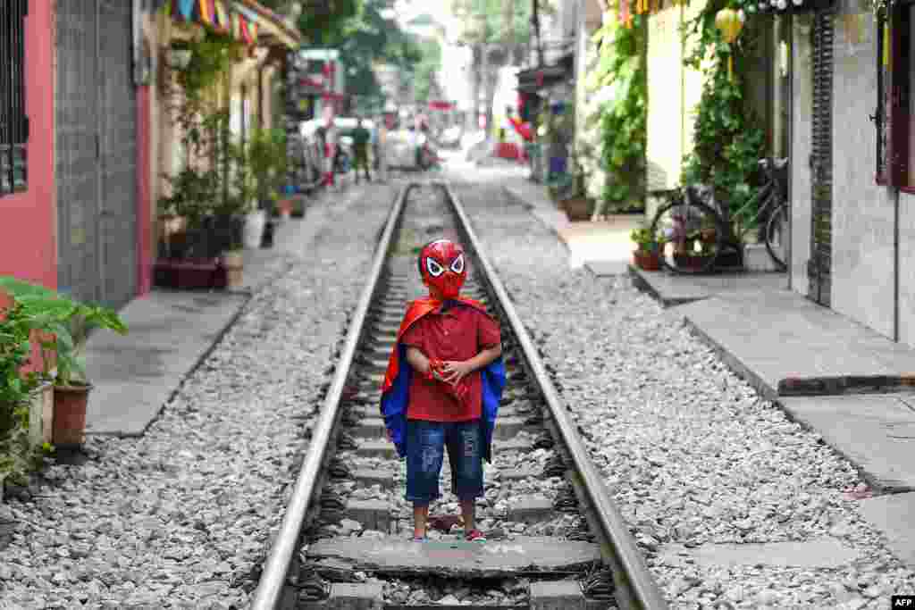 A boy wearing a Spiderman costume stands on Hanoi&#39;s popular train street, Vietnam.
