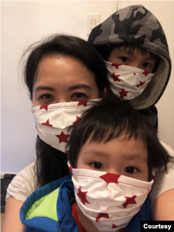 Nisakorn Quispe with her 2 and 6 years old son, Napat and Navin, wearing a protective face mask on April 18, 2020, at their home in Queens, New York City