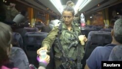 An Israeli solider hands out water on a bus, during the Syria Civil Defense, also known as the White Helmets, evacuation from the Golan Heights, Israel, in this still image taken from video, provided by the Israeli Army, July 22, 2018. 