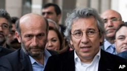 FILE - Can Dundar, right, editor-in-chief of Turkish opposition newspaper Cumhuriyet, and Erdem Gul, the paper's Ankara representative, speak to media outside an Istanbul courthouse, Nov. 26, 2015.