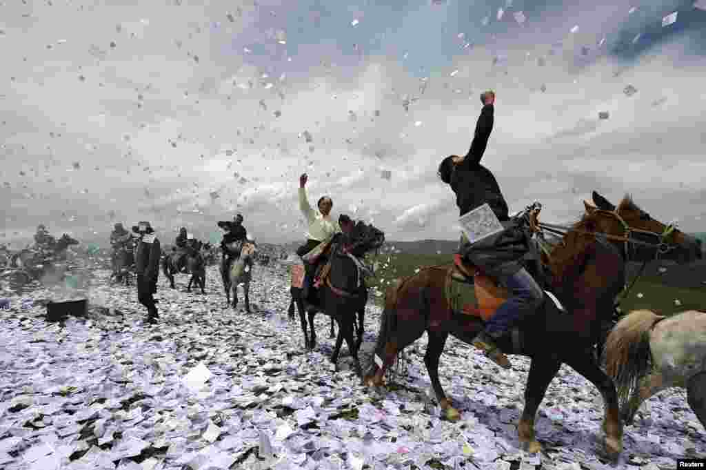 Tibetans on horseback throw praying papers as they gather for a traditional praying festival called &quot;Wei Sang&quot;, in Hongyuan county of Aba Tibetan and Qiang Autonomous Prefecture, Sichuan province, June 18, 2014.