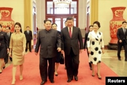 North Korean leader Kim Jong Un and wife Ri Sol Ju, and Chinese President Xi Jinping and wife Peng Liyuan walk together in Beijing, China, in this undated photo released by North Korea's Korean Central News Agency (KCNA) in Pyongyang March 28, 2018.