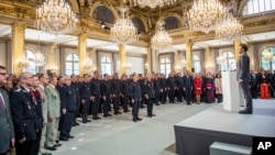 French President Emmanuel Macron stands at attention after addressing Paris Firefighters' brigade and security forces who took part at the fire extinguishing operations of the Notre Dame of Paris Cathedral fire, at the Elysee Palace in Paris, April 18, 2019.