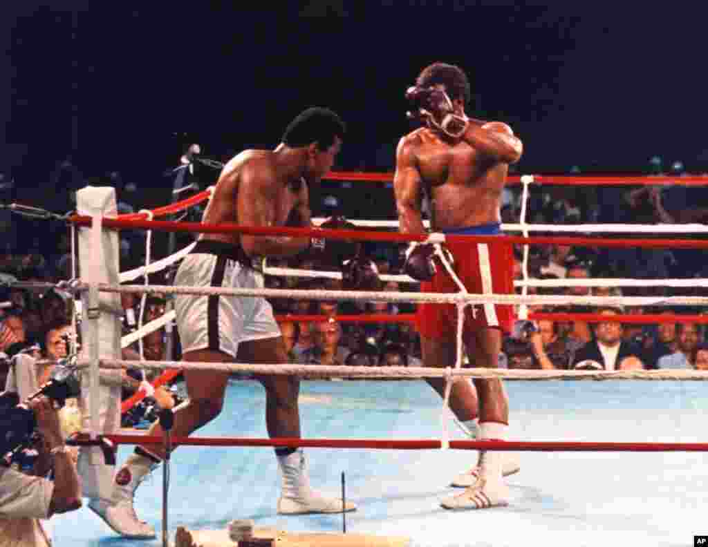 George Foreman, détenteur du titre au moment de la photo, se couvre avec une garde dégarnie, alors que Muhammad Ali décroche un jab (coup sec) au premier round de leur combat pour le titre des poids lourds à Kinshasa, au Zaïre, en Afrique, le 30 Octobre, 1974. Ali a repris le titre avec un KO au huitième round. (AP Photo / stf) 