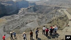 People stand atop a ridge overlooking the scene of a mudslide at a jade gemstone mining site, April 23, 2019, in Hpakant area of Kachin state, northern Myanmar. 