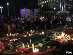 Candles and photos at a vigil for the victims and the injured of Orlando nightclub shooting. (S. Dizayee/VOA)