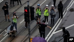 FILE - A protestor smashes a traffic light in Hong Kong, Sunday, Oct. 6, 2019. In Hong Kong, traffic light signals make a special sound so that people who do not see well can safely cross the road.(AP Photo/Vincent Thian)