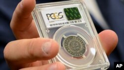 In this July 31, 2017, image made from a video, David McCarthy, a senior numismatist at Kagin's, holds what is believed to be the first coin ever struck by the U.S. government at the World's Fair of Money in Denver, Colorado.