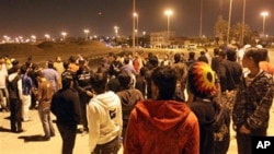 A row of riot police stand between two groups of Bahraini youths in the early hours of Friday in Hamad Town, March 4, 2011