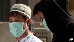 FILE - Muslim pilgrims wear surgical masks to help prevent infection by the MERS respiratory virus in Mecca, Saudi Arabia, May 13, 2014.