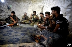 FILE - Syrian rebels eat in a cave in which they also live, on the outskirts of the northern town of Jisr al-Shughur, Idlib province, Syria, west of the city of Idlib, Sept. 9, 2018.