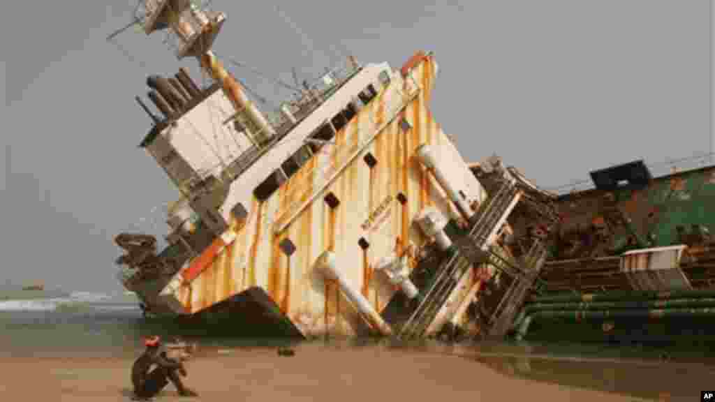 A man sits near an abandoned ship that lays beached near Takwa Bay just off the coast of Nigeria.