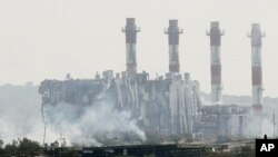 Smoke is seen in front of a damaged building by the power station in Mari on July 11, 2011 after huge explosions, reportedly from seized munitions, rocked the nearby Greek-Cypriot "Evangelos Florakis" naval base leaving several dead and injured.