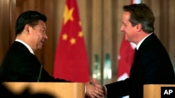 Presiden China Xi Jinping (kiri) berjabat tangan dengan PM Inggris, David Cameron, dalam konferensi pers bersama di London, Rabu (21/10).