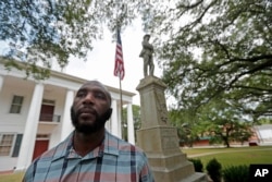 In this Aug. 1, 2018 photo, Ronnie Anderson, an African-American man charged with possession of a firearm by a convicted felon, poses in front of a confederate statue on the lawn of the East Feliciana Parish Courthouse.