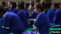 FILE - A prisoner carries her daughter during a ceremony at Prey Sar prison in Phnom Penh, March 8, 2015. Twenty-two female prisoners who are either pregnant or have kids were released by the Cambodian government for International Women's Day. 