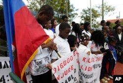 Widnay Charles, left, bows his head during a vigil to commemorate the seventh anniversary of the earthquake that devastated Haiti in 2010, Jan. 12, 2017, in the Little Haiti neighborhood of Miami.