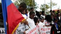 Widnay Charles, agoch, bese tèt li pandan yon rasanbleman pou komemore gwo tranblemandtè ki te detui prèske yon bò nan peyi Dayiti sa gen 7 tan deja, 12 janvye 2010. Ti-Ayiti (Little Haiti), Miami, Florid. 12 janvye 2017.