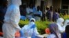 FILE - Congolese and WHO officials prepare equipment before the launch of vaccination campaign against the deadly Ebola virus near Mangina village, DRC, Aug. 8, 2018. Congo has now begun the first-ever trial to test the effectiveness and safety of four experimental Ebola drugs.