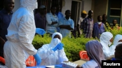 FILE - Congolese and WHO officials wear protective suits as they prepare equipment before the launch of vaccination campaign against the deadly Ebola virus near Mangina village, near Beni in North Kivu province, DRC, Aug. 8, 2018.