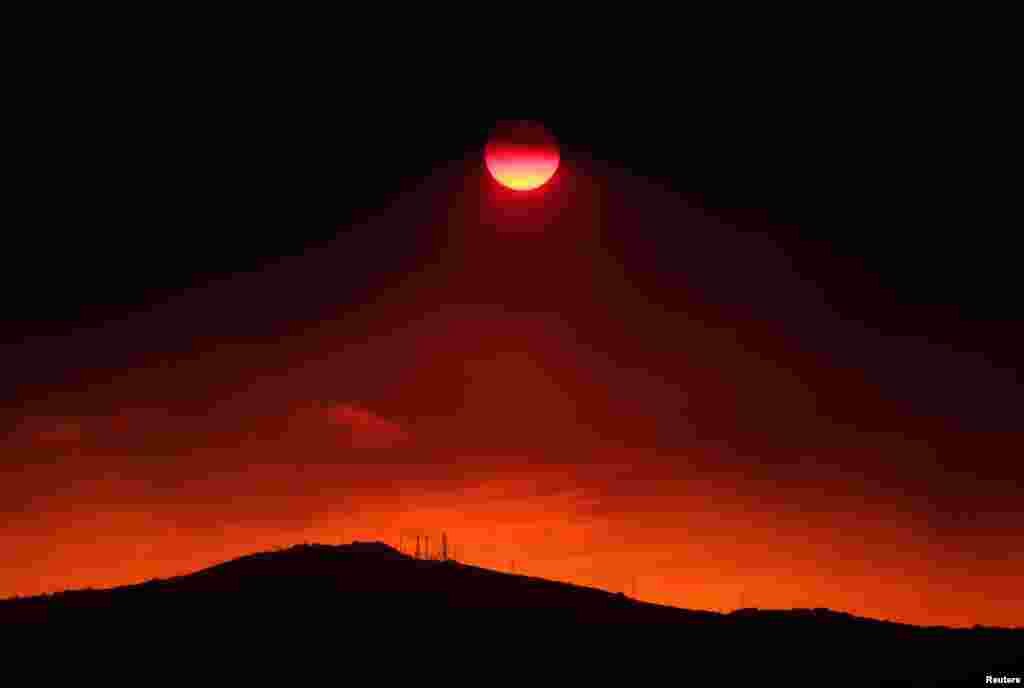 The sun sets under a cloud of smoke caused by a wildfire fanned by strong winds on the island of Evia, in Athens, Greece, Aug. 12, 2018.