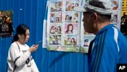 People walk past a poster warning against foreign spies in an alley in Beijing, China, April 20, 2016. China is marking National Security Education Day with the poster warning female government workers about dating foreigners, who could turn out to have s