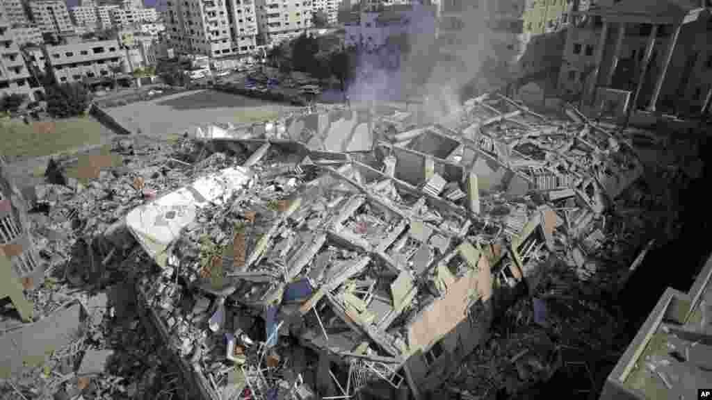 Asap mengepul dari reruntuhan gedung apartemen Al-Zafer menyusul serangan udara Israel Sabtu yang meruntuhkan bangunan berlantai 13 itu di Gaza City (24/8).&nbsp;(AP/Adel Hana)