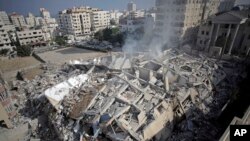 Smoke rises from the rubble of the Al-Zafer apartment tower following Israeli airstrikes Saturday that collapsed the 13-story building, in Gaza City, Sunday, Aug. 24, 2014.