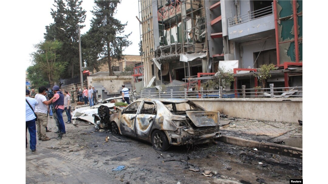 Journalists and civilians stand near the damage after rockets fired by insurgents hit the al-Dabit maternity clinic in government-held parts of Aleppo city, Syria, in this handout picture provided by SANA, May 3, 2016.