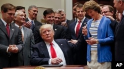 President Donald Trump, gives the pen he used to sign an Executive Order to Sen. Lisa Murkowski, R-Alaska, right, in the Roosevelt Room of the White House in Washington, April 28, 2017. The Executive Order directs the Interior Department to begin review of restrictive drilling policies for the outer-continental shelf.