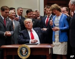 President Donald Trump, gives the pen he used to sign an Executive Order to Sen. Lisa Murkowski, R-Alaska, right, in Washington, April 28, 2017. The order directs the Interior Department to begin review of restrictive drilling policies for the outer-continental shelf.