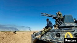 Shi'ite fighters sit on a military vehicle in Al Hadidiya, south of Tikrit, en route to the Islamic State-controlled al-Alam town, where they are preparing to launch an offensive on Saturday, March 7, 2015.