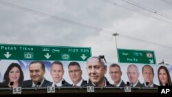 A man works on a Likud party election campaign billboard depicting Israeli Prime Minister Benjamin Netanyahu, center, and his party candidates, in Petah Tikva, April 1, 2019.