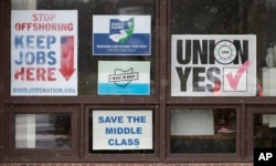 FILE - Signs hang from windows at the UAW Local 1112 union hall in Lordstown, Ohio, Nov. 27, 2018.