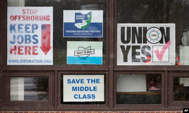 Signs hang from windows at the UAW Local 1112 union hall, Nov. 27, 2018, in Lordstown, Ohio.