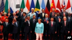 U.S. President Barack Obama, front row third from left, Chinese President Xi Jinping, second from right, and other leaders wave as they pose for a group photo session for the G-20 Summit held at the Hangzhou International Expo Center in Hangzhou.