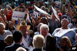 Republican presidential candidate Donald Trump shakes hands during a campaign rally at Wings Over the Rockies Air and Space Museum, Friday, July 29, 2016, in Denver.