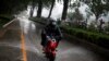 Seorang pria mengendarai skuter listrik Niu melaju melewati genangan air saat badai di Beijing, China, 21 Mei 2020. (Foto: REUTERS/Thomas Peter)