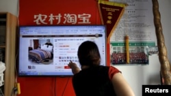 A customer points at a screen displaying a website of Alibaba's Taobao at a rural service center in Yuzhao Village, Tonglu, Zhejiang province, China, July 20, 2015. 