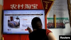 A customer points at a screen displaying a website of Alibaba's Taobao at a rural service center in Yuzhao Village, Tonglu, Zhejiang province, China, July 20, 2015. 