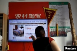 A customer points at a screen displaying a website of Alibaba's Taobao at a rural service center in Yuzhao Village, Tonglu, Zhejiang province, China, July 2015.