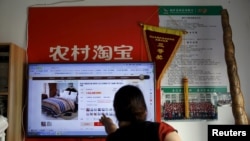 FILE - A customer points at a screen displaying a website of Alibaba's Taobao at a rural service center in Yuzhao village, Tonglu, Zhejiang province, China, July 20, 2015. 