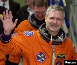 File-This Nov. 30, 2000 file photo shows mission specialist Marc Garneau of Canada waving to photographers as he leaves the Operations and Checkout Building.