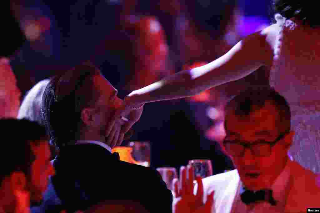 French actress Marion Cotillard touches U.S. actor Leonardo Di Caprio on the cheek during an auction at the amfAR's Cinema Against AIDS 2014 event in Antibes at the 67th Cannes Film Festival in France, May 22, 2014.