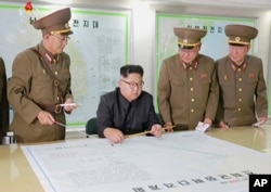 ຮູບພາບຖ່າຍຈາກ ວີດີໂອ ໃນວັນທີ 14 ສິງຫາ 2017 ຈາກອົງການຂ່າວເກົາຫລີເໜື້ອ KRT ສະແດງໃຫ້ເຫັນຜູ້ນຳເກົາຫລີເໜືອ ທ່ານ Kim Jong Un ກຳລັງຖືກລາຍງານໃຫ້ຊາບ ຢູ່ນະຄອນພຽງຢາງ.