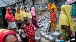 Rohingya women and children wait in a queue to collect water at the Leda camp, an unregistered camp for Rohingya in Teknaf, Bangladesh.