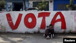 A man rests near a sign that reads 'vote' on a street in Comas on the outskirts of Lima, Peru, March 4, 2016. 