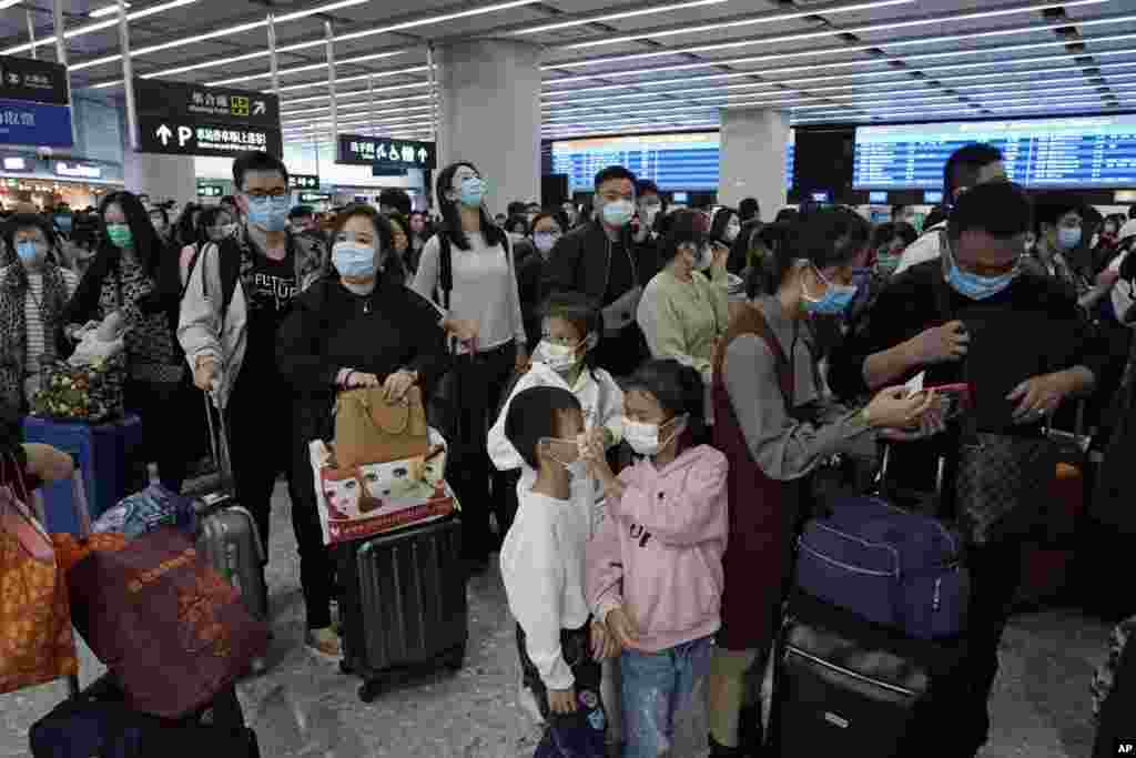 مسافران هنگ کنگی با ماسک&zwnj;های محافظ به دلیل شیوع ویروس کرونا در چین، در انتظار سوار شدن به قطار به صف ایستاده اند.