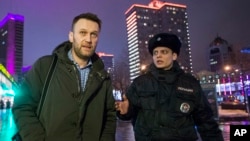 Russian opposition activist and anti-corruption crusader Alexei Navalny (l) is detained by police after defying his house arrest to speak on Radio Echo Moskvy in Moscow, Jan. 14, 2015.